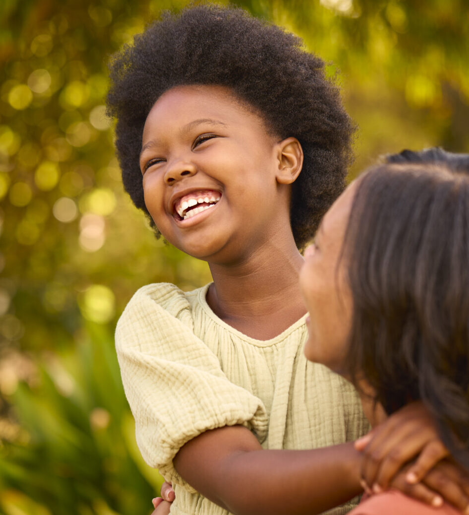 Loving Mother And Daughter Laughing And Hugging Outdoors In Countryside Or Garden