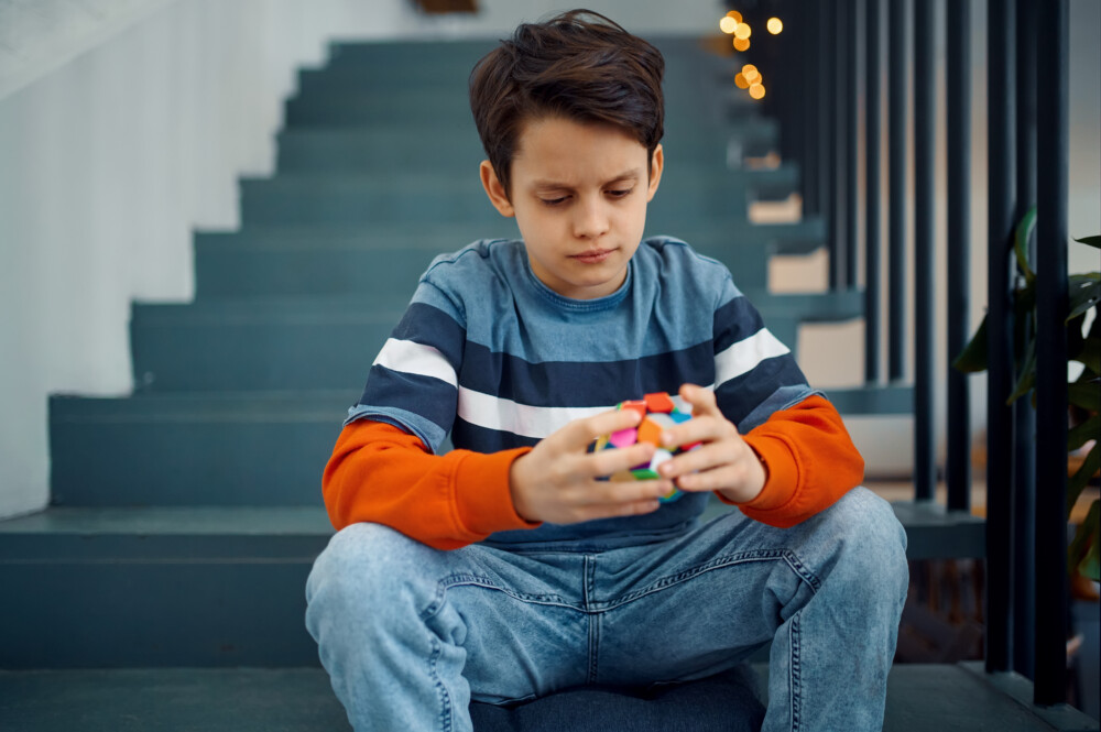 ADHD/ADD Telehealth Care for Families Nationwide. Thoughtful little boy play with puzzle cubes